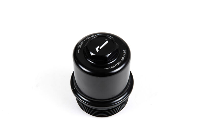 dsg-oil-filter-housing-dq250_45869756811_o-scaled-1jpg - OPSHOLDERS Close-up of a black camera lens or cap from above, with white text around the rim and a central knob/marking.
