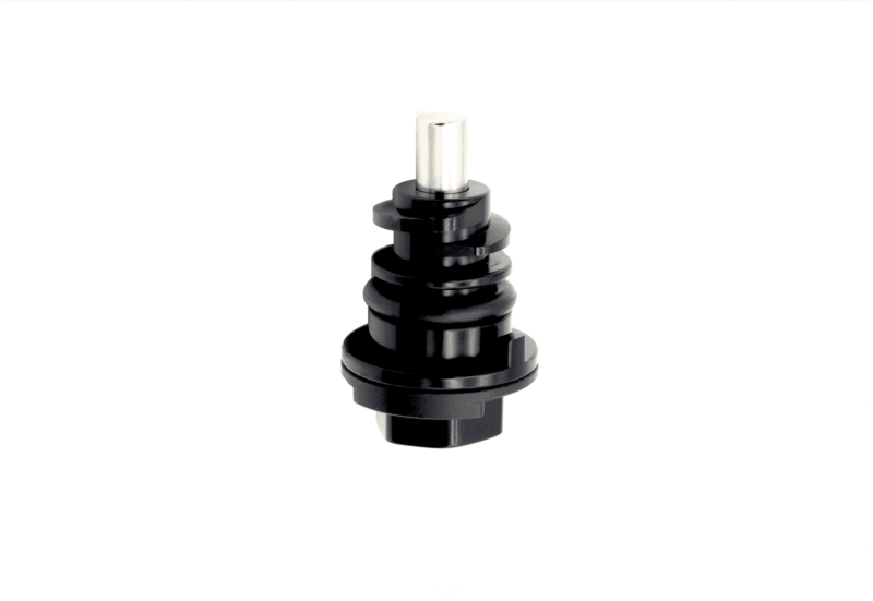 Close-up of a black, multi-tiered cylindrical mechanical part with a silver top pin on white background.
