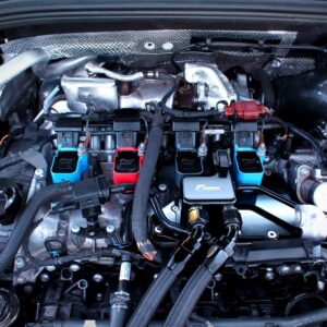 Close-up of a car engine bay with blue and red aftermarket coil packs and wiring harnesses