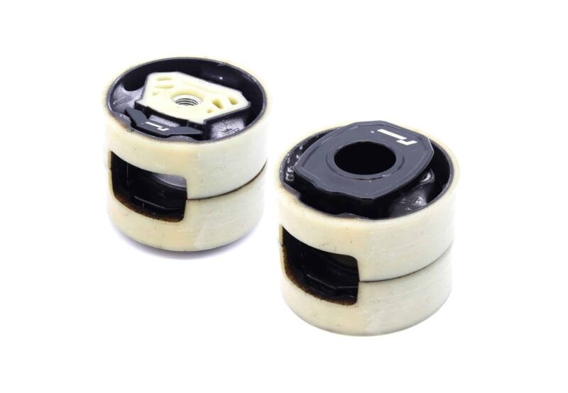 lower-motor-mount-twin-dogbone-inserts_52732183553_o-scaled-3jpg - OPSHOLDERS Close-up of two white plastic caster wheels with black inner cores and exposed bearings, showing signs of wear and dirt.