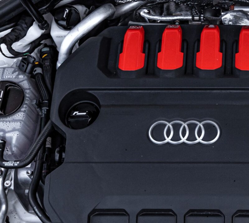 oil-cap-gen4-mqb-evo_51747283825_o-1jpg - OPSHOLDERS Close-up of an Audi engine bay: black engine cover with four red ignition coil covers and the Audi ring logo visible on the front.
