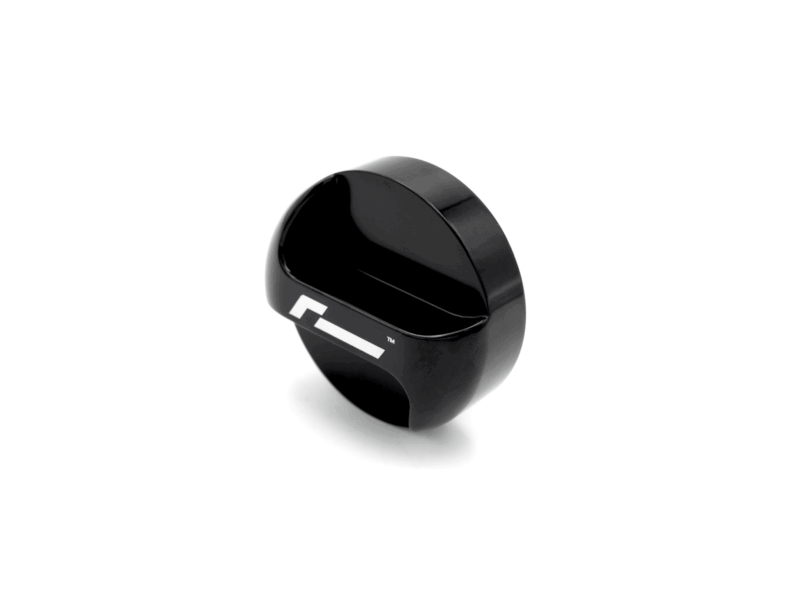 oil-cap-gen4-mqb-evo_51747283960_o-1png - OPSHOLDERS Close-up of a glossy black circular device with a white stripe, on a white background, viewed at an angle.