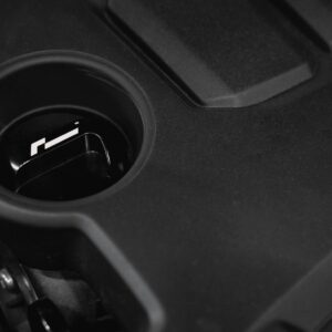 oil-cap-gen4-mqb-evo_51826422583_o-1jpg - OPSHOLDERS Close-up of a car cup holder with a small black component resting inside the holder edge of a vehicle interior
