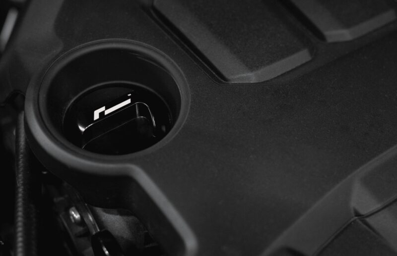 oil-cap-gen4-mqb-evo_51826422583_o-1jpg - OPSHOLDERS Close-up of a car cup holder with a small black component resting inside the holder edge of a vehicle interior