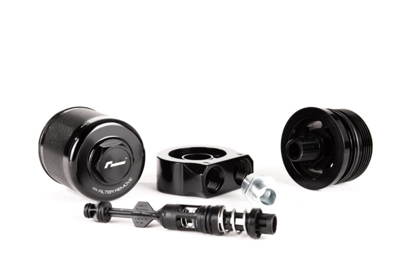 oil-cooler-vwr18-g700_45869747881_o-scaled-1jpg - OPSHOLDERS Disassembled black camera lens parts and metal fittings arranged on a white surface.
