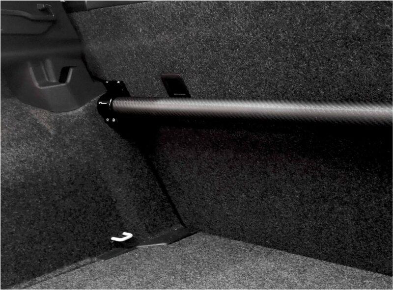 Close-up of a car interior showing a pedal and textured floor mat from the driver’s side.