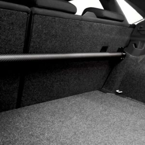 Car trunk interior with folded rear seats and a long cylindrical rod along the carpeted floor (black and white).