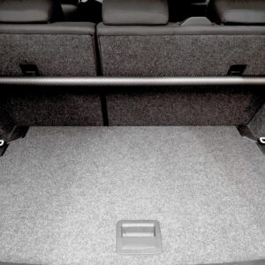 Rear cargo area of a car with a long black carbon‑fiber crossbar spanning the space behind the folded rear seats.