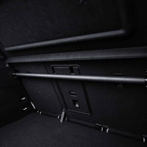Dark car trunk interior with a horizontal cargo rail, side LED light, and folded rear seats visible in the back.