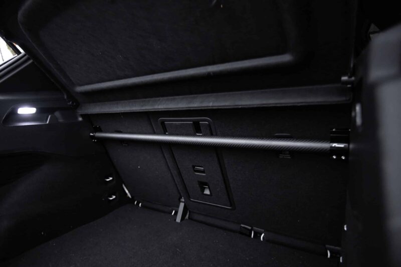 Dark car trunk interior with a horizontal cargo rail, side LED light, and folded rear seats visible in the back.