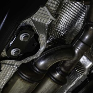 propshaft-bearing-alignment-kit_51769411775_o-scaled-2jpg - OPSHOLDERS Close-up of a vehicle’s exhaust pipe and mounting bracket with heat shielding and braided insulation visible underneath.