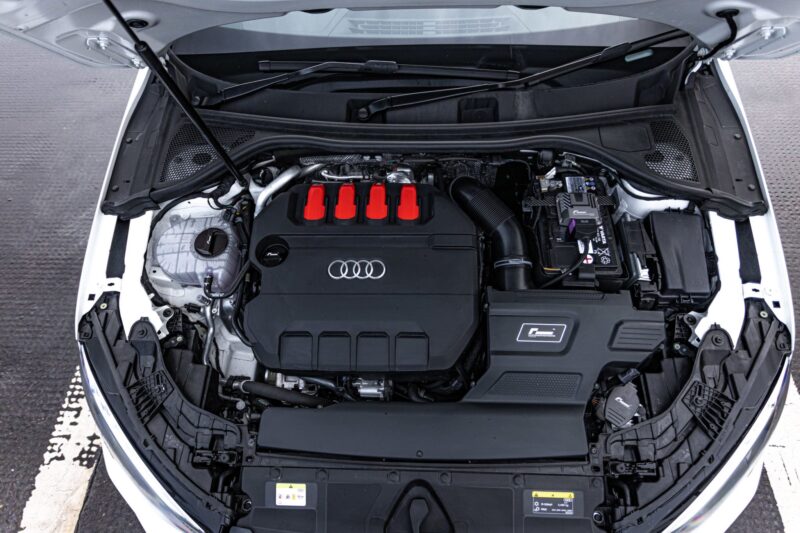r600-evo_51817392042_o-scaled-2jpg - OPSHOLDERS Open car hood shows an engine bay with a black cover featuring four red-tipped ignition coil covers and Audi rings badge in the center of the engine bay.