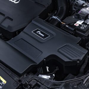 r600-evo_51818344591_o-scaled-2jpg - OPSHOLDERS Close-up of a car's engine bay highlighting the battery and surrounding plastic covers.