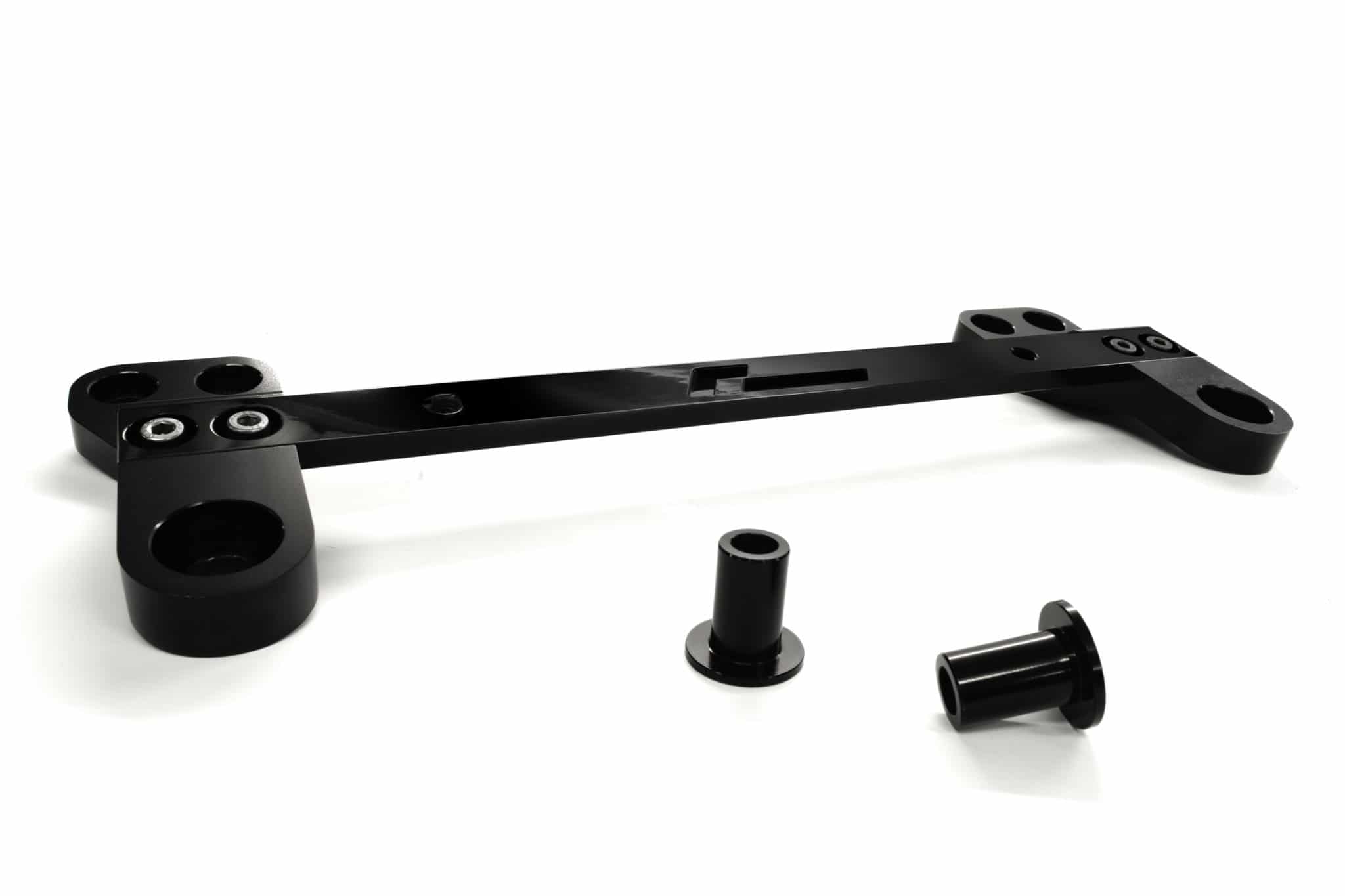 racingline-front-subframe-brace-14_51825053237_o-scaled-2jpg - OPSHOLDERS Black metal frame pieces with circular holes and cylindrical connectors spread on a white surface.