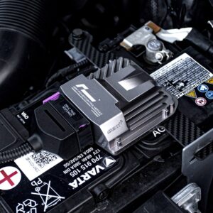 Car battery with a metal heatsink/module attached to the top, likely a performance electronic control unit on the terminal area