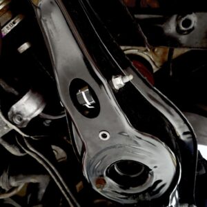 Close-up of a black metal motorcycle frame with bolts and circular openings, revealing mechanical components in a tight shot.