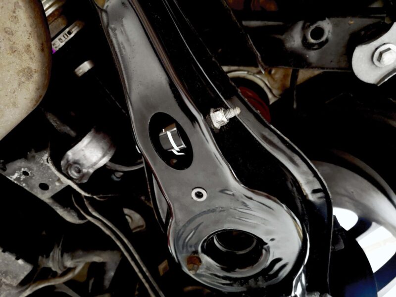 Close-up of a black metal motorcycle frame with bolts and circular openings, revealing mechanical components in a tight shot.