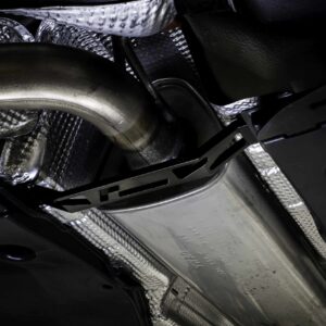 Close-up of a vehicle’s undercarriage showing metallic heat shields and dark chassis components nearby.