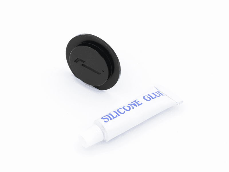 Round black wireless charging pad beside a white tube labeled Silicone Glue on a white background.