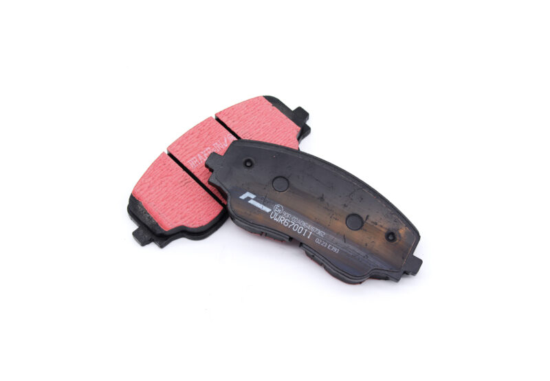 Two red brake pads with black backing plates on a white background, showing wear marks and mounting surfaces for a disc brake system