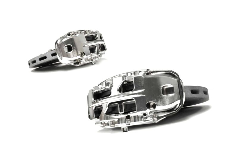 stage-3-ccm-brake-kit_50586722876_o-scaled-2jpg - OPSHOLDERS Close-up of two shiny metal watch buckles with black straps on a white background, showing their clasps and holes.