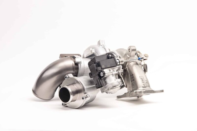 Close-up of a metallic turbocharger component with pipes and a black actuator on a white background