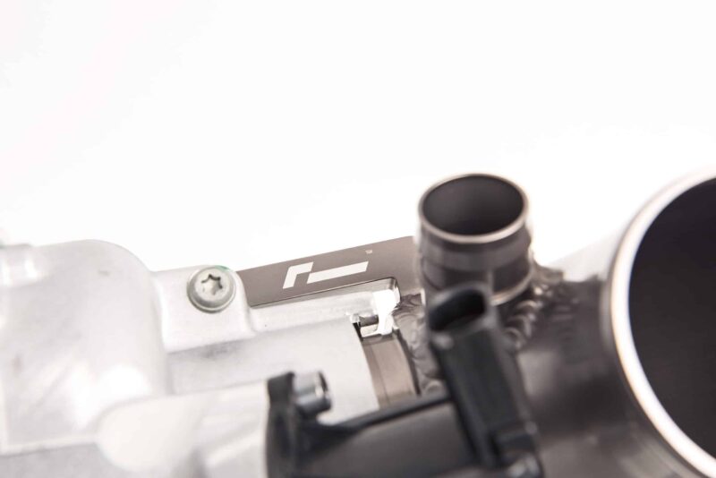 Close-up of a metallic precision instrument showing a black circular dial on the right, screws and wiring in the foreground, a blurred background.