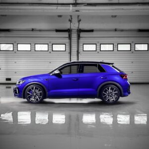 vw-t-roc-r-sport-springs_52959630586_ojpg - OPSHOLDERS Blue SUV parked inside a dim, empty garage with white metal roll doors and a reflective floor on the scene's right side.