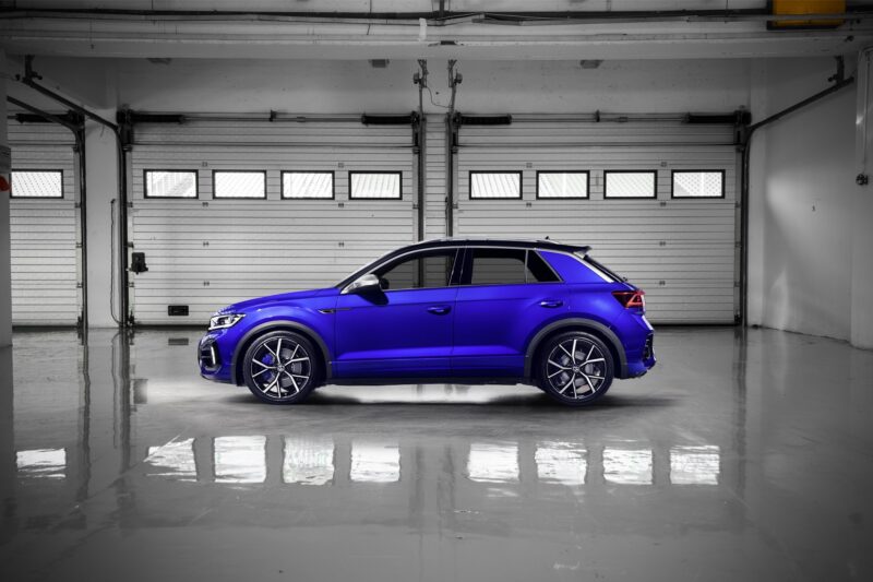 vw-t-roc-r-sport-springs_52959630586_ojpg - OPSHOLDERS Blue SUV parked inside a dim, empty garage with white metal roll doors and a reflective floor on the scene's right side.