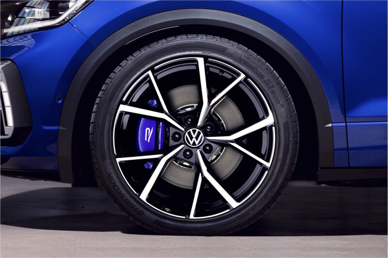 vw-t-roc-r-sport-springs_52959778584_ojpg - OPSHOLDERS Close-up of a blue VW car wheel showing a black and silver alloy rim and blue brake caliper behind the spokes.