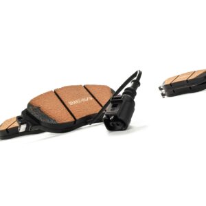 Close-up of tan friction-material brake pads with black backing plates and a sensor wire, laid on a white background.