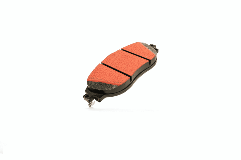 Automotive brake pad with red friction material on a black backing plate, shown at an angle.