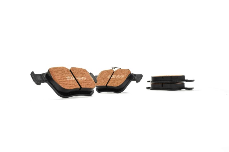 Two brown textured bicycle pedal surfaces with black frames on a white background; shows pedals with traction pads and no visible toe cages.