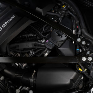 DSC02599 - OPSHOLDERS BMW engine bay with a black engine cover labeled 'BMW M Power' and surrounding hoses and components.