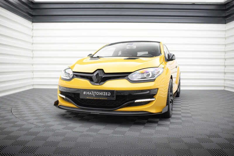 pol_po_Bonnet-Vents-459_7jpg - OPSHOLDERS Front view of a bright yellow Renault car parked in a white, industrial-looking showroom with a black grille and a '#MAXTONIZED' license plate-like banner in front