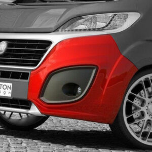 Close-up of a two-tone red and gray van front with a prominent grille and Maxton Design badge on the bumper, showing a large alloy wheel nearby