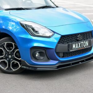 pol_po_FRONT-SPLITTER-V-1-suitable-for-Suzuki-SWIFT-6-SPORT-8268_2jpg - OPSHOLDERS Close-up of a bright blue car’s front-left section, showing the headlight, grille, and a 'MAXTON' license plate in a parking lot.