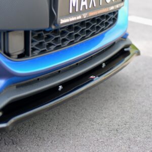 pol_po_FRONT-SPLITTER-V-1-suitable-for-Suzuki-SWIFT-6-SPORT-8268_4jpg - OPSHOLDERS Close-up of the front of a blue car showing a honeycomb grille and carbon-fiber lip under the bumper, with part of the license plate visible.