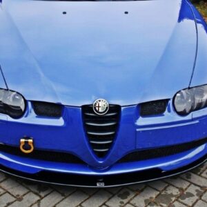 pol_po_FRONT-SPLITTER-suitable-for-Alfa-Romeo-147-GTA-621_2jpg - OPSHOLDERS Front view of a blue Alfa Romeo car on brick pavement, displaying the emblem, dual headlights, and yellow tow hook in the lower left corner.
