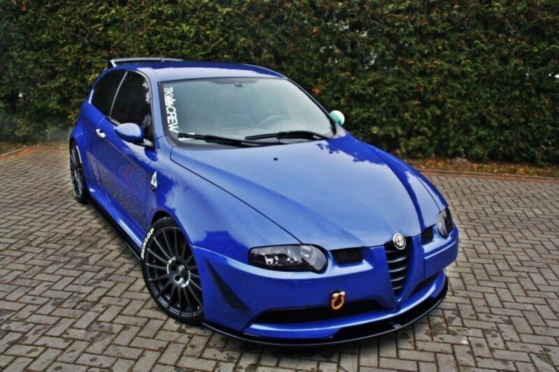 pol_po_FRONT-SPLITTER-suitable-for-Alfa-Romeo-147-GTA-621_4jpg - OPSHOLDERS Blue Alfa Romeo hatchback with black multi‑spoke wheels parked on a brick driveway, front tow hook visible.