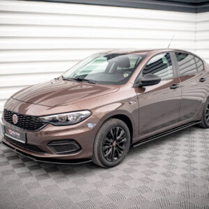 Front three-quarter view of a brown Fiat sedan parked indoors, with a white corrugated wall background and checkered floor pattern.