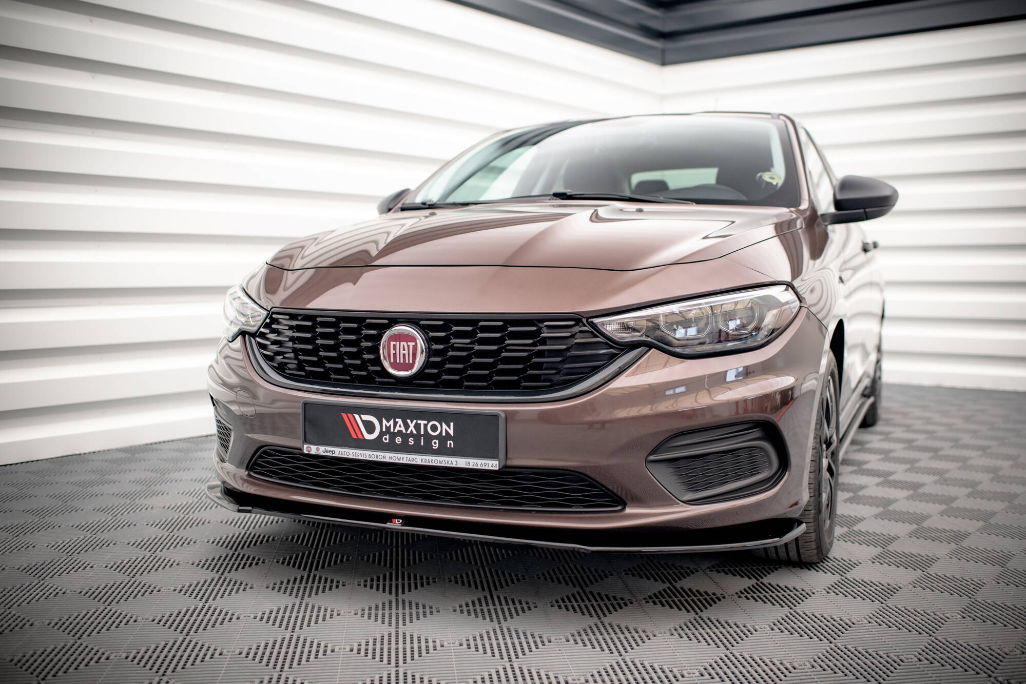 Bronze Fiat car front view with logo, grille and headlights in a showroom setting.