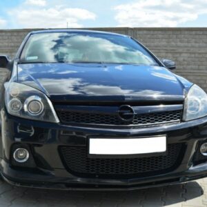 Front view of a black Opel hatchback parked on a paved area with a brick wall behind.