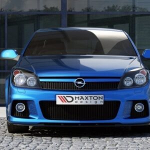 Front view of a blue sports hatchback with a Maxton design plate, parked on a cobblestone driveway in front of a glass-front building.