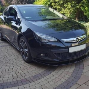 pol_po_FRONT-SPLITTER-suitable-for-Opel-ASTRA-J-GTC-835_1jpg - OPSHOLDERS Black Opel hatchback parked on a circular paved driveway with greenery in the background, reflecting sunlight on its surface.