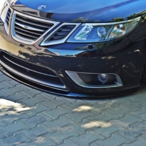 Black car front with lowered bumper and lip spoiler on a paved driveway.