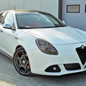 White Alfa Romeo hatchback parked on gray pavers beside a light-gray building with a large garage door