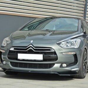 Grey Citroën hatchback parked on a paved lot in front of a modern building with horizontal metal siding.