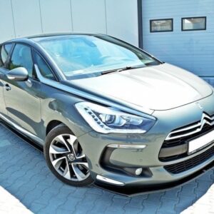 Gray Citroën hatchback parked on a paved lot in front of a light gray industrial building with a large garage door