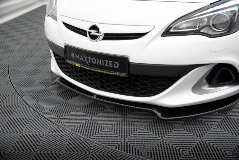 Front view of a white Opel car, emblem visible, with a black plate reading #MAXTONIZED on a showroom floor.